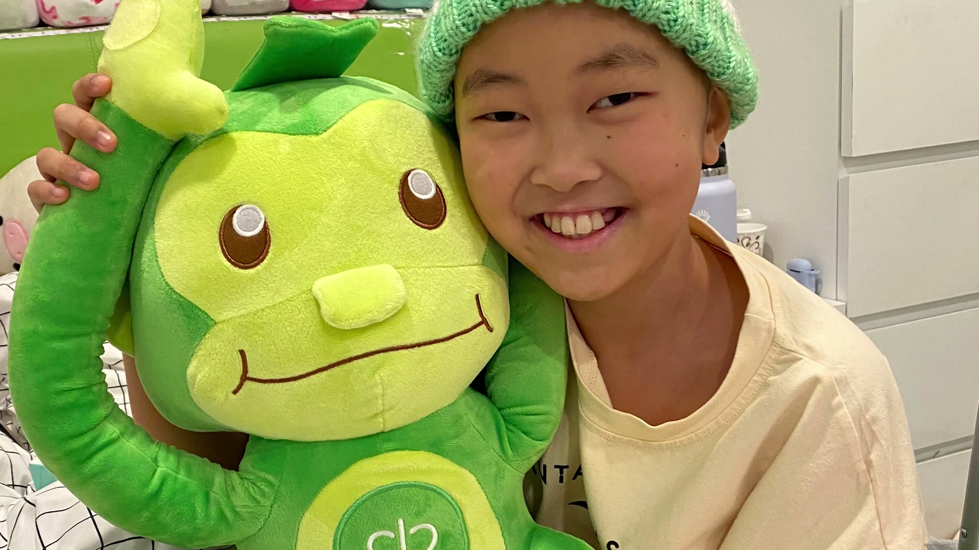 A young patient in a green beanie holding Hope, the green monkey.