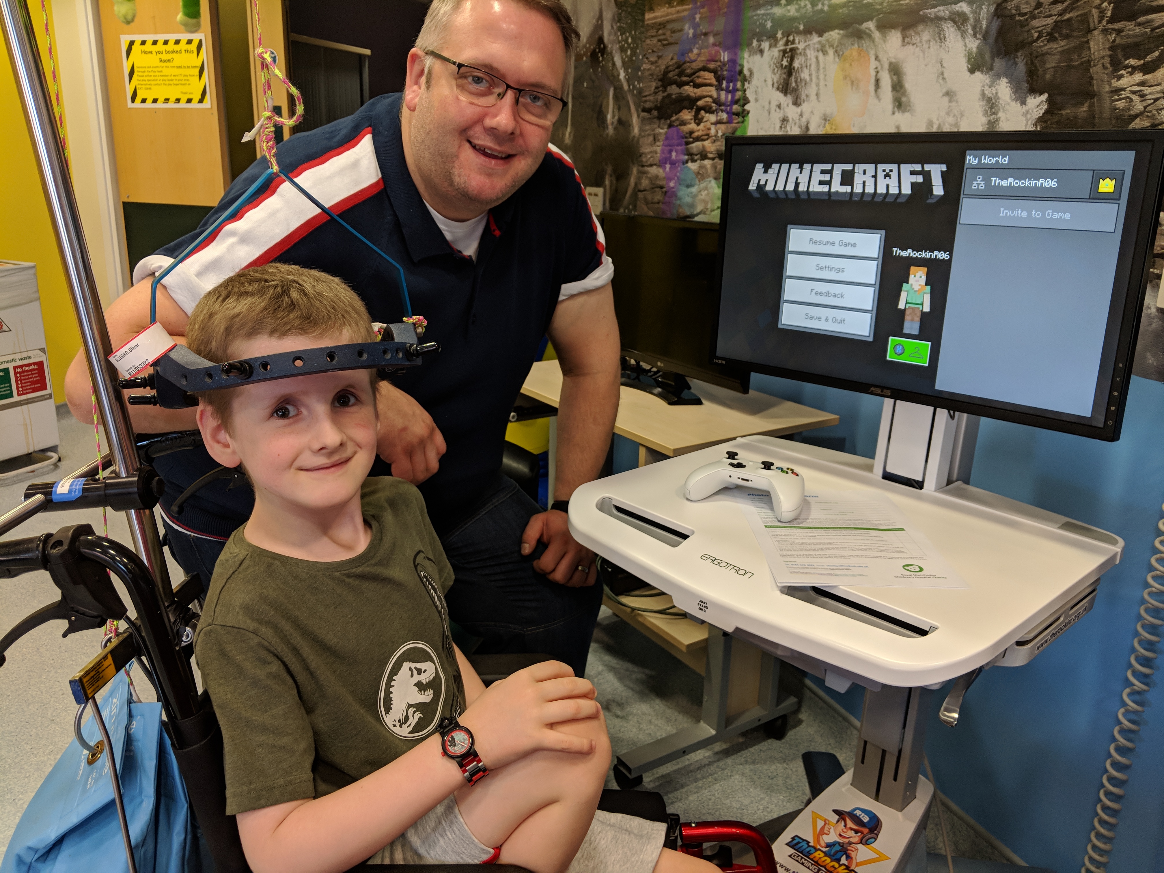 A boy playing Minecraft on an Xbox cart in his hospital room.